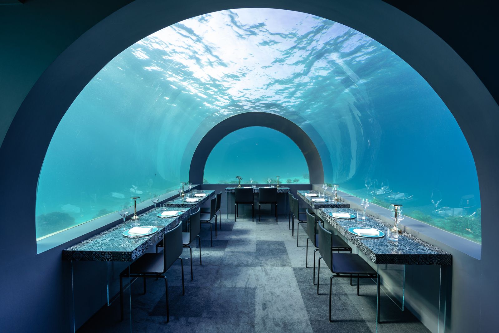 An underwater restaurant in the Maldives — tables beneath an acrylic tunnel with the reef above